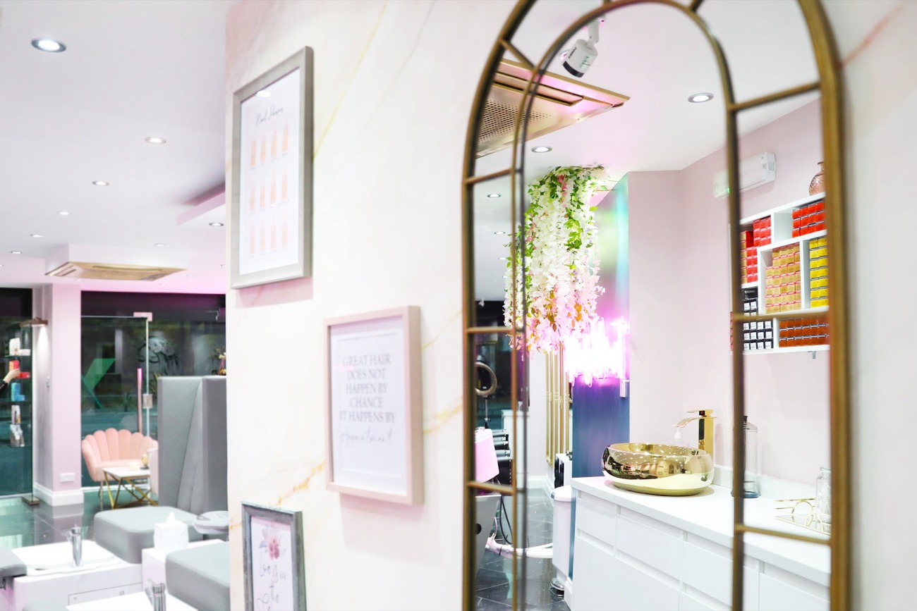 A gold arched mirror and framed prints inside MyBeautyHub, with a sign reading great hair happens by appointment